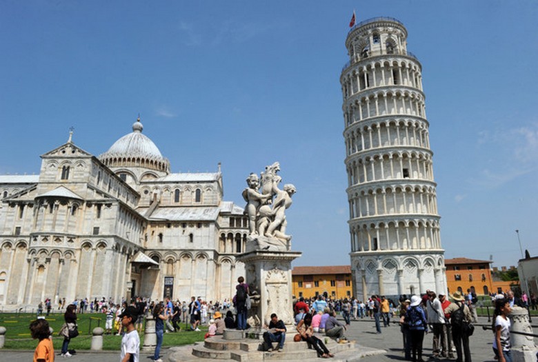 Számos turista fokozatosan kiegyenlíti a pisa ferde torony lejtését.